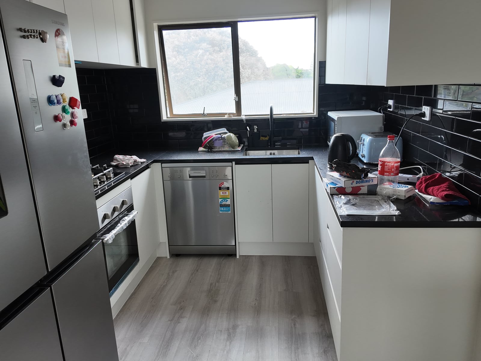 Renovated white kitchen with black worktops and splashback