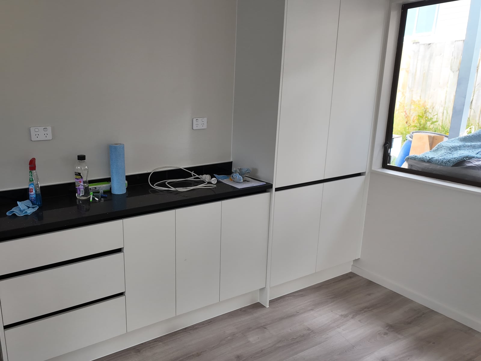 Long run of white storage cabinetry beside the renovated kitchen