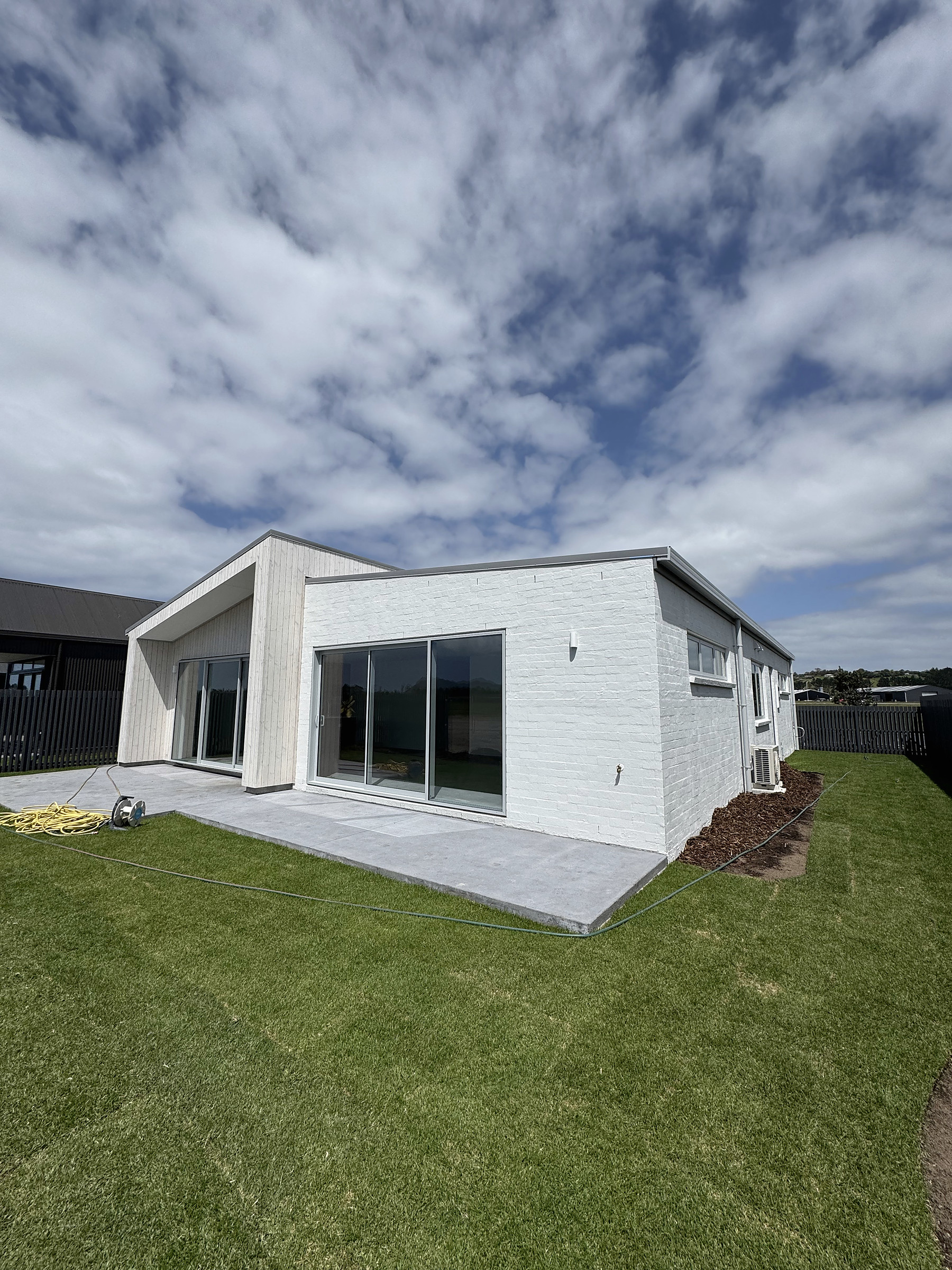 Garden elevation framed by lawn, vertical shiplap and bagged brick