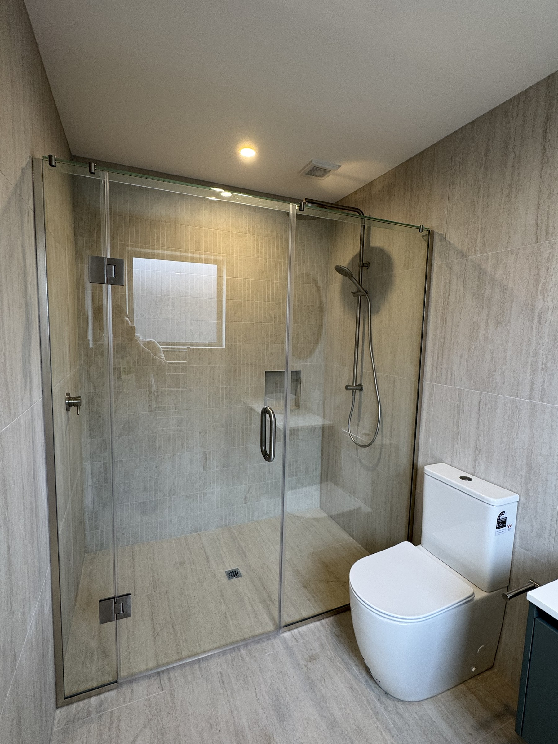 Ensuite with frameless glass shower and full-height tiling
