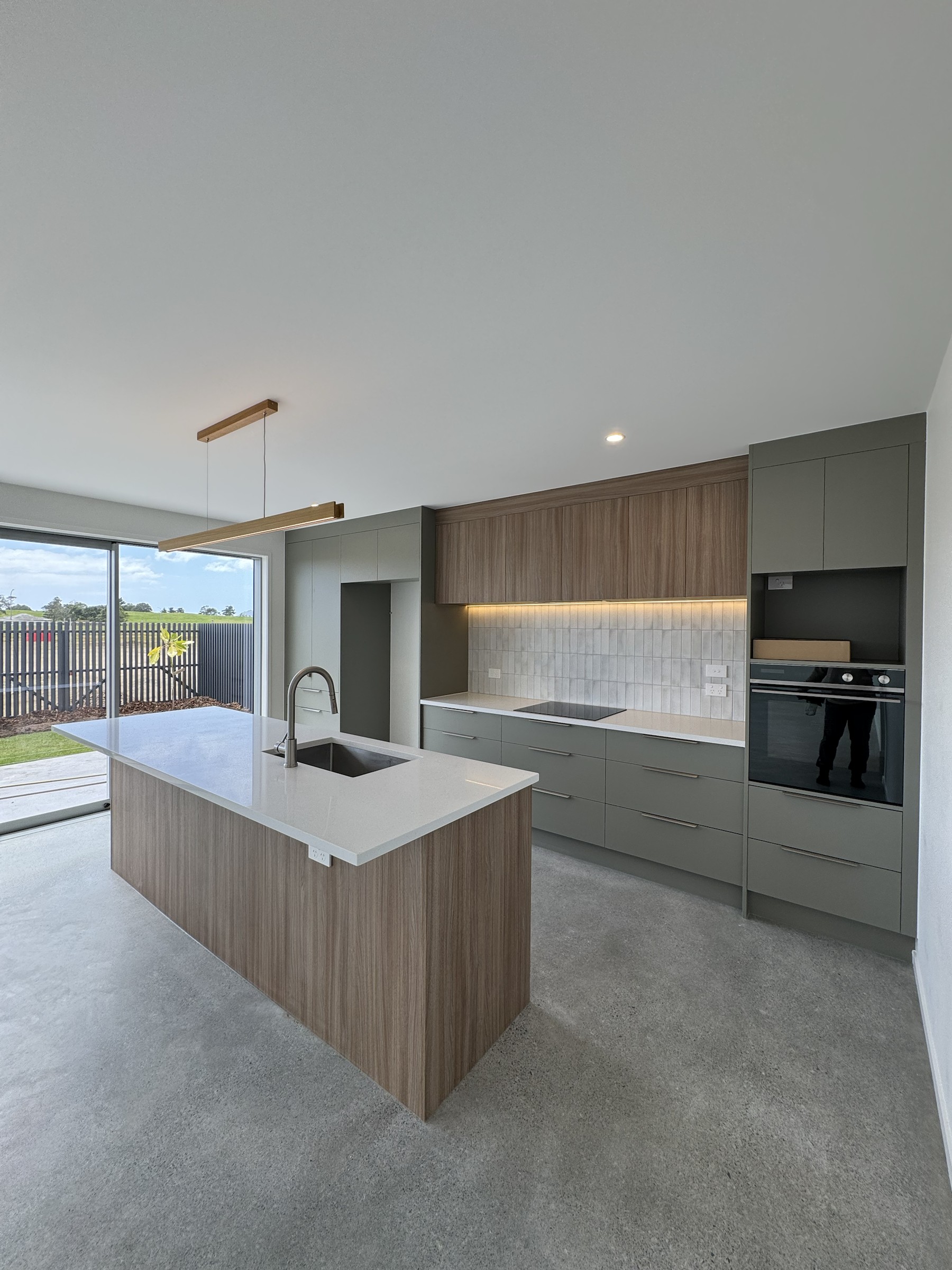 Kitchen viewed across the polished concrete living area