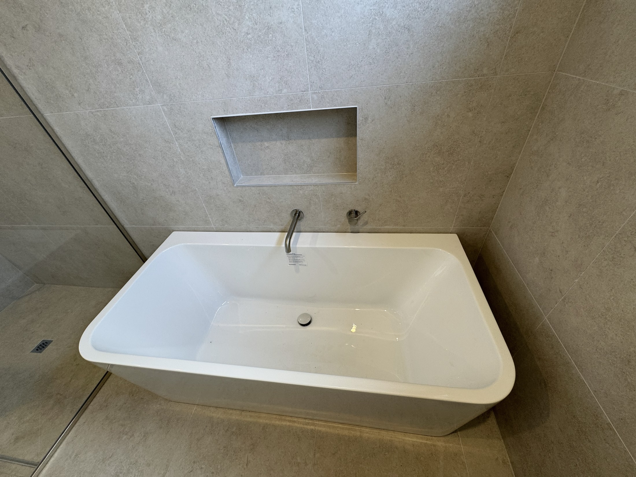 Back-to-wall bath beneath a tiled shower niche