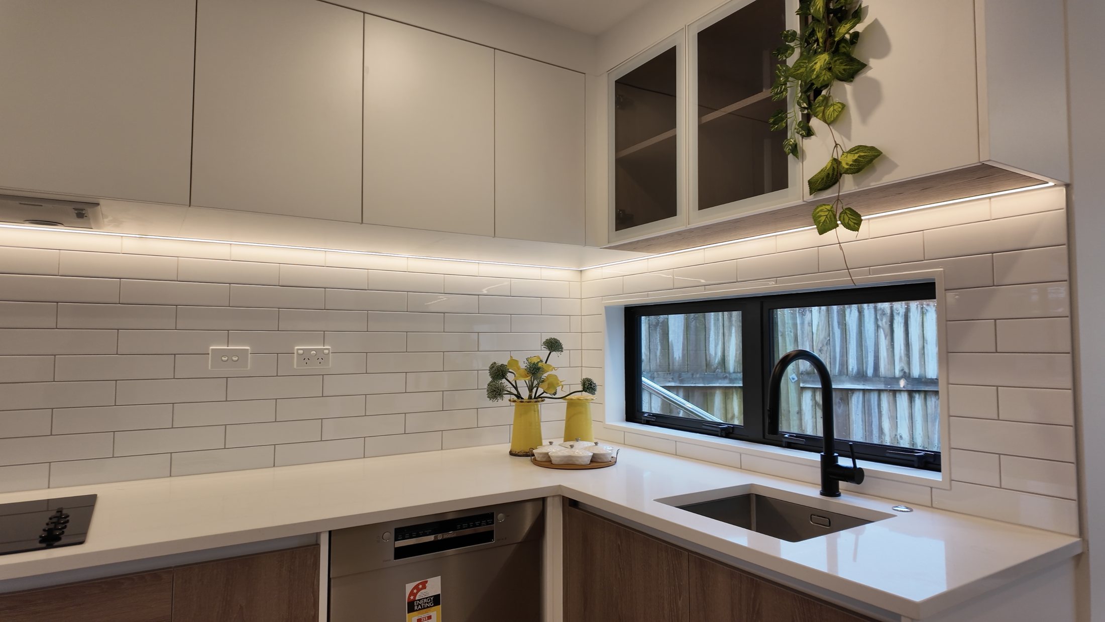 Kitchen sink beneath a black-framed window with tiled splashback
