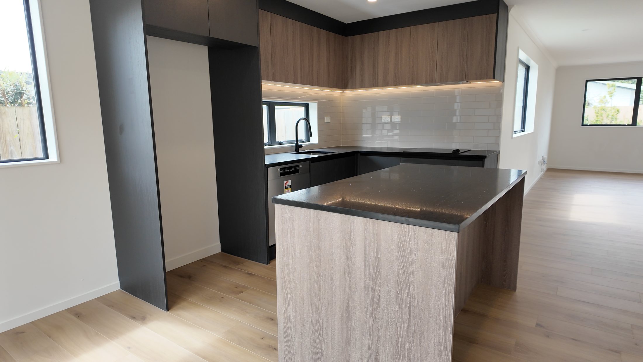 Completed open-plan kitchen with timber cabinetry and black worktops