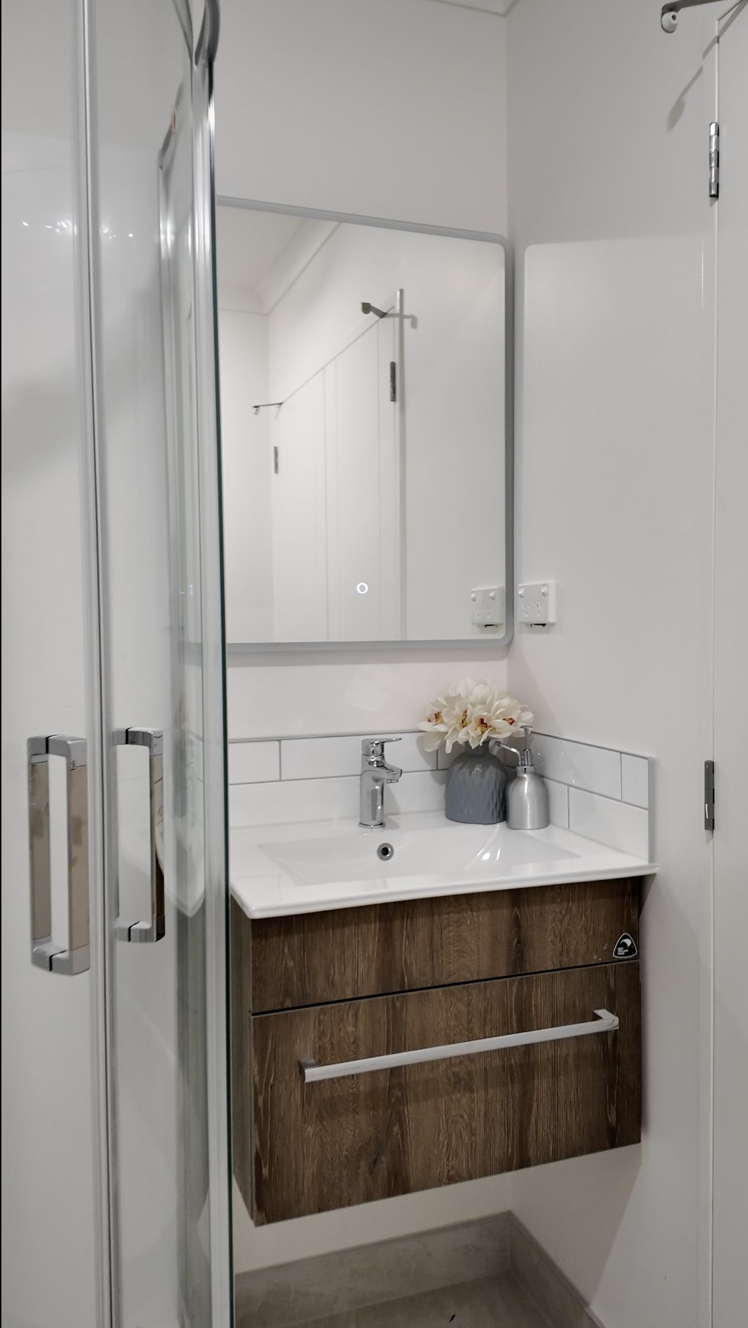 Compact bathroom vanity with timber-grain drawers and tiled splashback