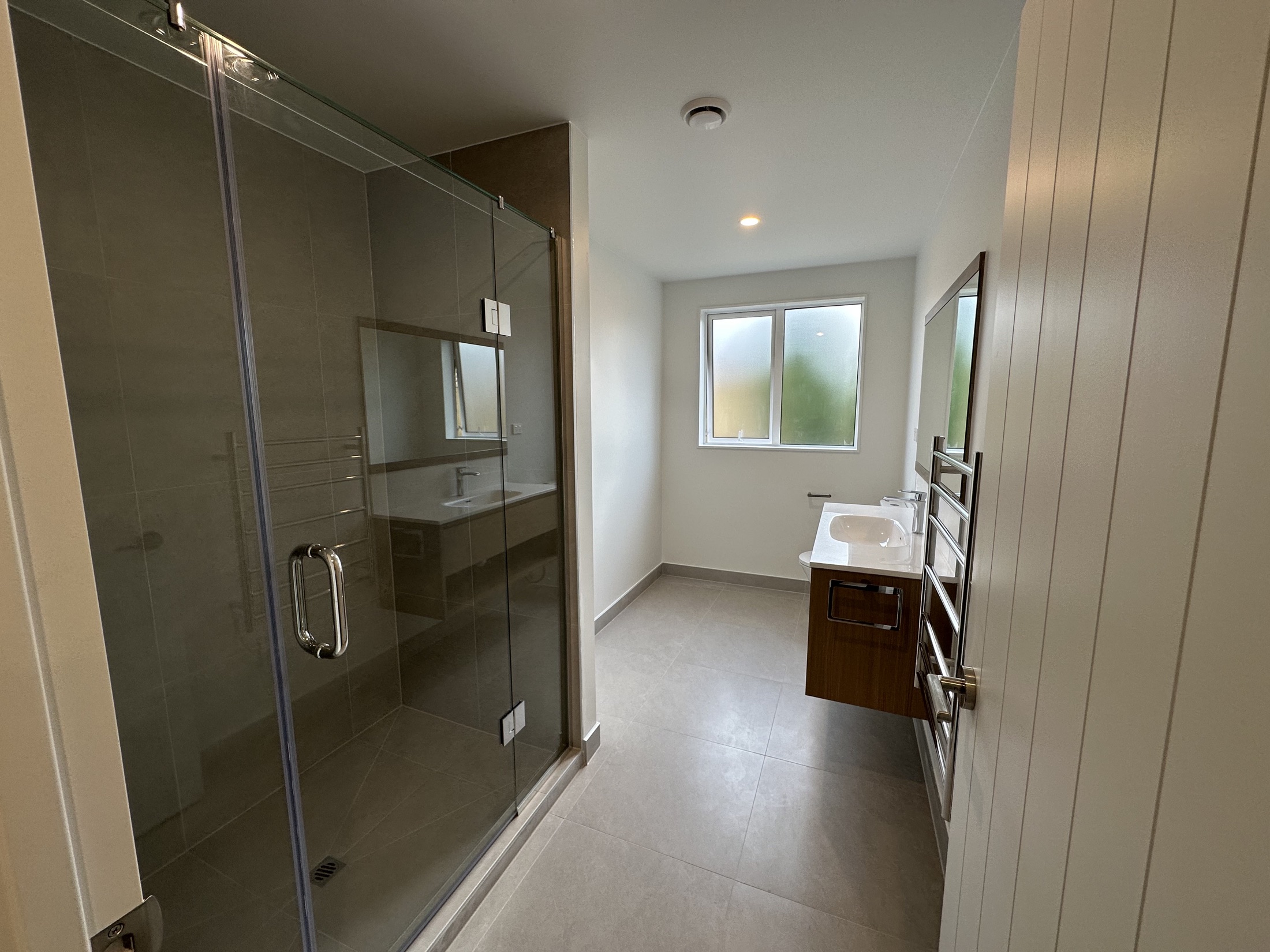 Completed bathroom with tiled shower and floating vanity