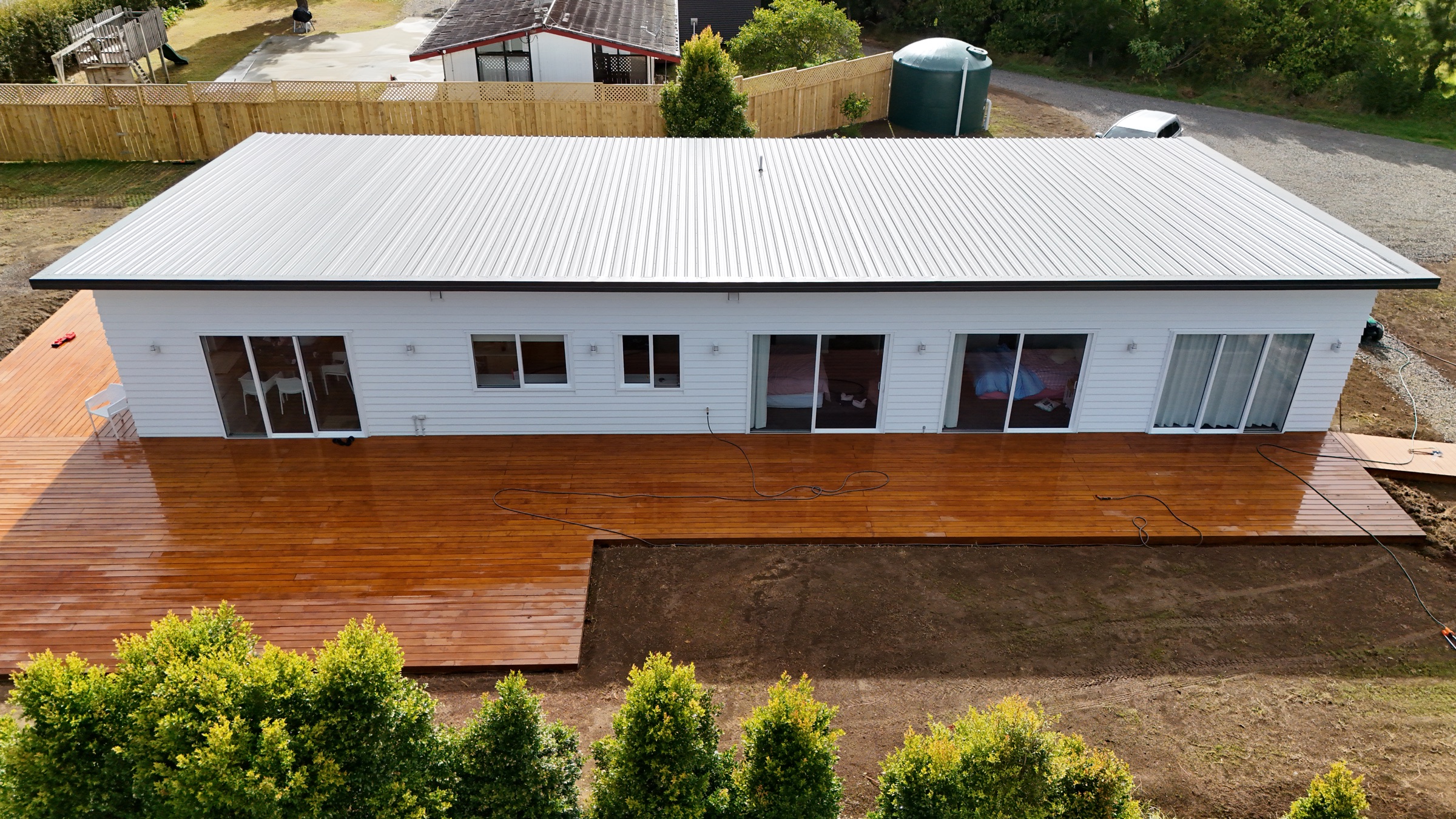 Completed white weatherboard home and wide timber deck in Whenuapai